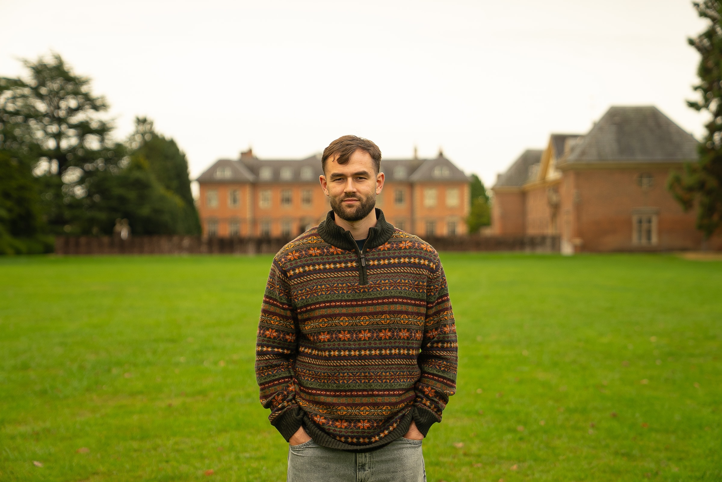 Luke Watkins, founder of Social Flow, standing on the lawn in front of a red brick manor house