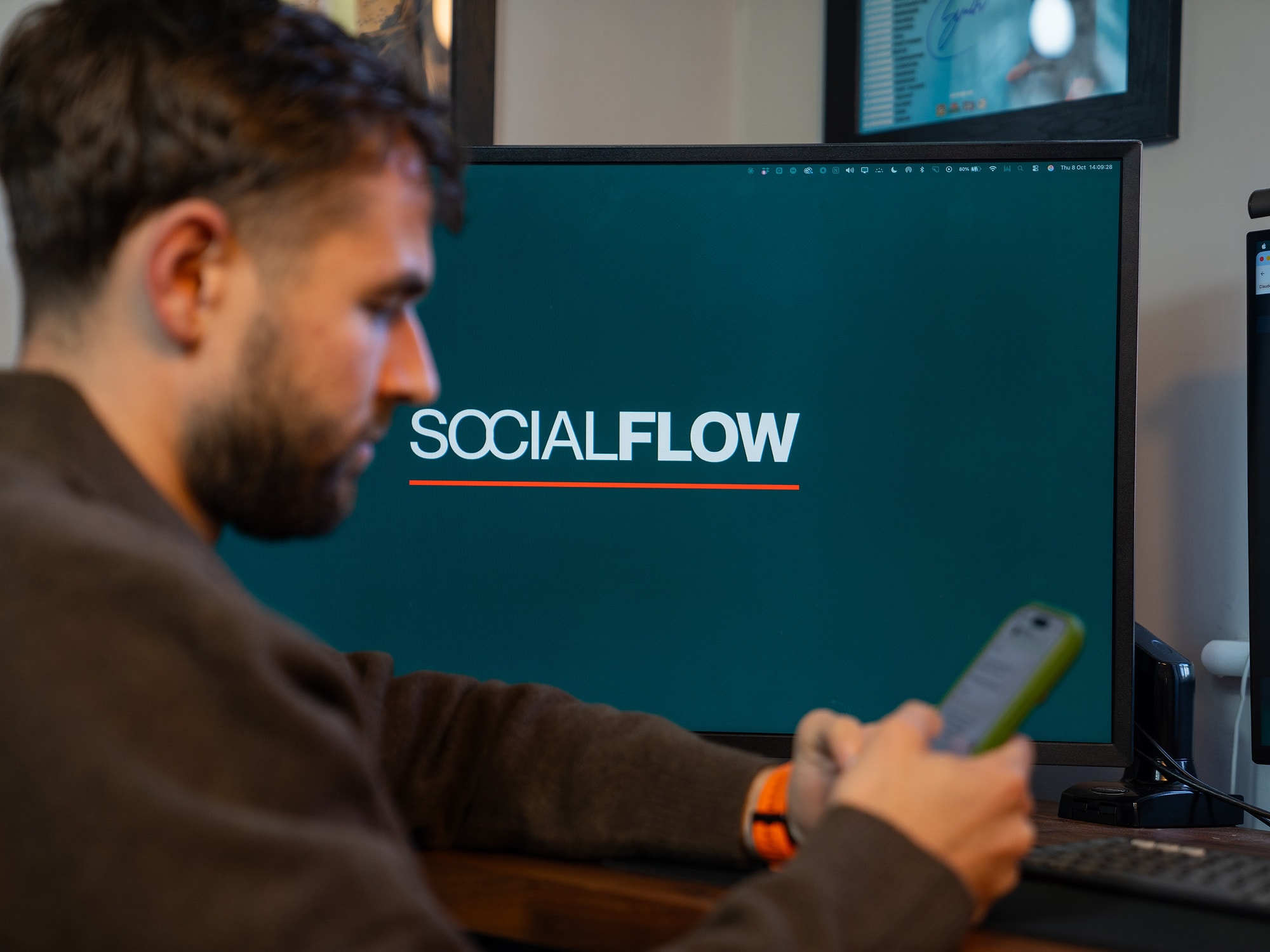 Luke Watkins checking his phone in front of the Social Flow screen